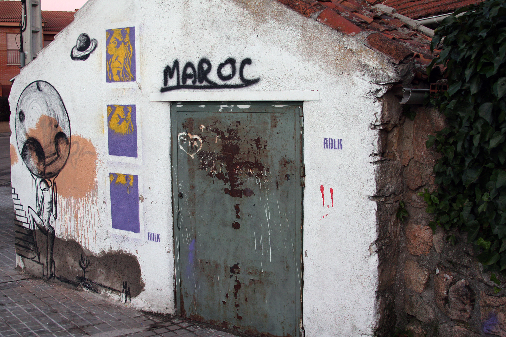 A small whitewashed building covered in graffiti