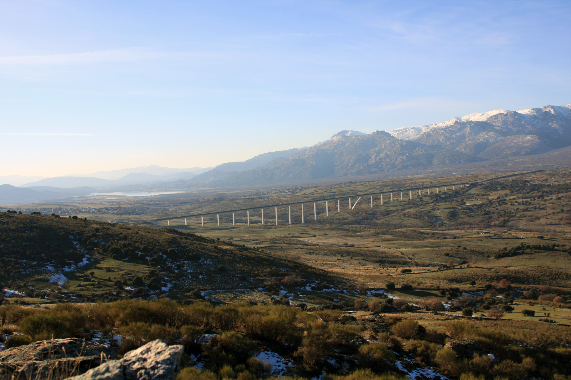 View over a sunny valley, with a long bridge and mountains in the distance