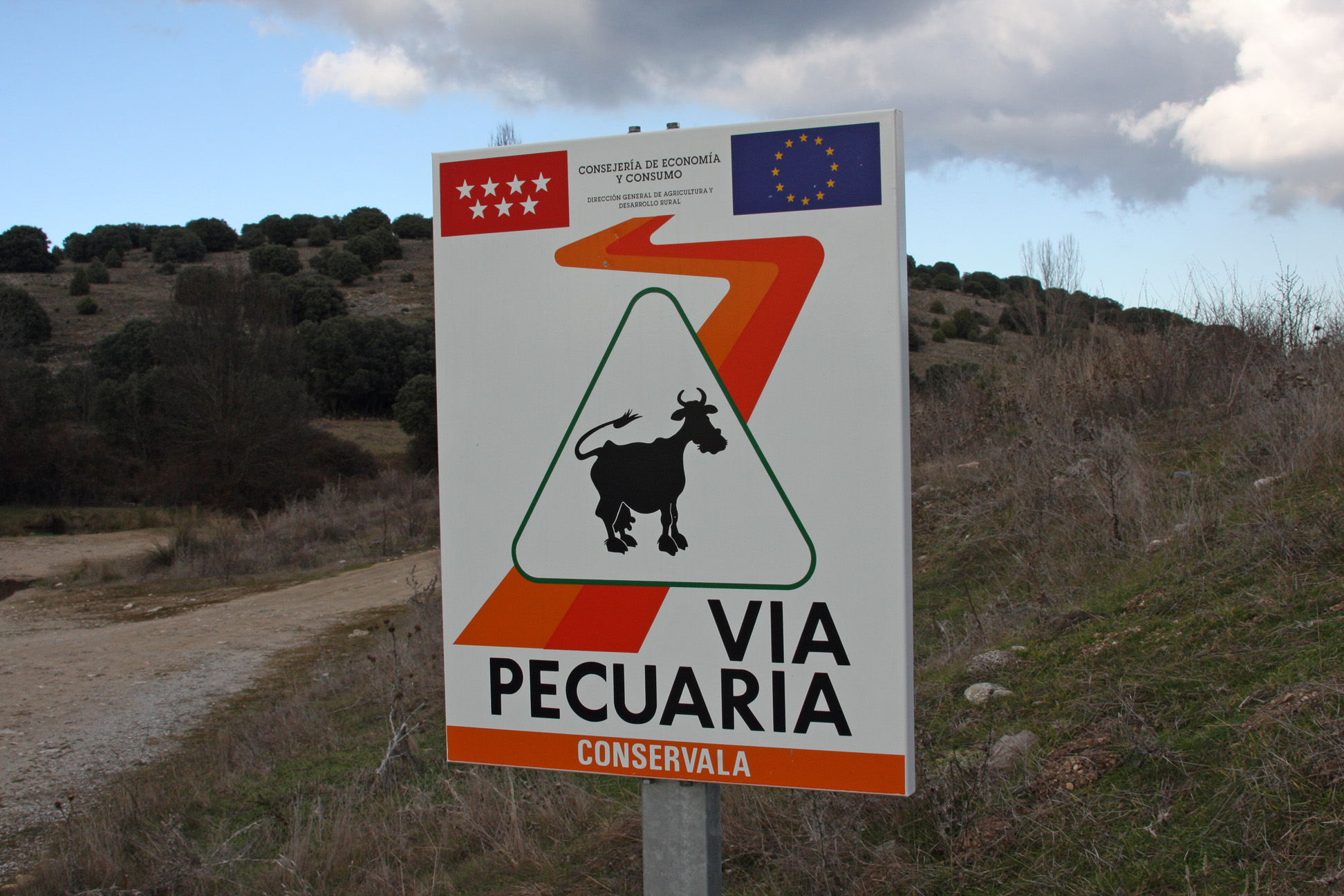 A sign that reads 'Via Pecuaria' next to a footpath